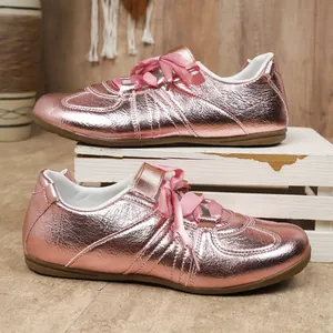 Détail de baskets GAT rose métallisé avec d'élégants lacets en ruban de satin sur bois