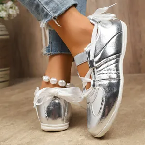 Gros plan de chaussures d'entraînement allemandes argentées avec lacets en ruban blanc.