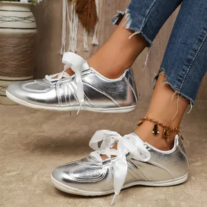Gros plan de baskets argentées pour femmes avec d'élégants lacets en ruban blanc.