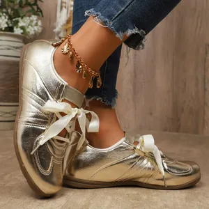 Gros plan sur des baskets dorées métallisées avec lacets en ruban et chevillère