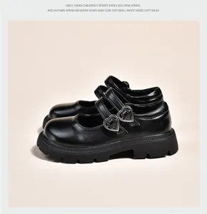Détail de chaussures en cuir noir pour filles avec des boucles en forme de cœur.