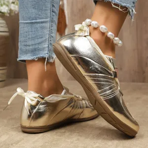 Gros plan de chaussures plates dorées pour femmes avec lacets ruban et perles
