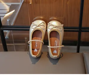 Close-up of elegant champagne gold girls princess shoes with a bow and strap detail.