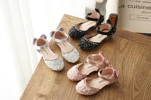 Elegant detail of glittery girls princess dress shoes with bow accents and ankle straps.