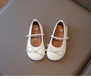 Detailed view of white girl's princess shoes with elegant bowknot and glossy finish