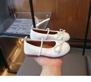 Close-up of white girls' Mary Jane shoes with cute bow and patent leather finish