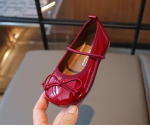 Detailed close-up of glossy red patent leather girl's shoes featuring a cute bow.