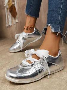 Close-up of silver metallic German Army Trainer sneakers with elegant white ribbon laces
