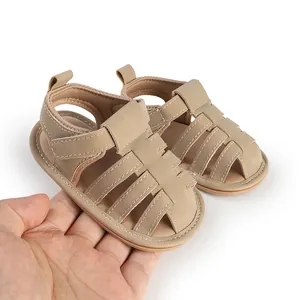 Detail van zachte baby sandalen in kaki in de hand gehouden voor de schaal