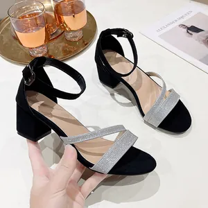Détail de sandales noires à talons carrés avec brides pailletées et boucle cheville.