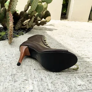 Close-up of brown lace-up jazz dance boots with wood grain high heels on concrete.