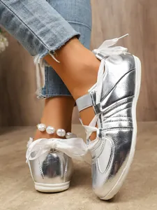 Close-up detail of silver metallic GAT style sneakers featuring elegant white ribbon laces