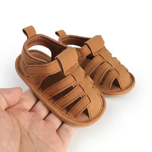 Detailopname van bruine baby sandalen met zachte zolen, met de hand vastgehouden.