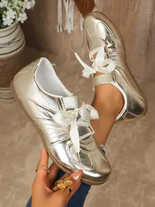Close-up view of gold metallic German Army Trainer sneakers with white ribbon laces.