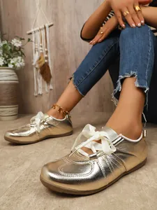 Gold metallic German Trainer sneakers with white ribbon laces for a chic vintage look