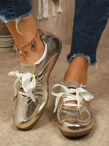Close-up of golden metallic sneakers with elegant white ribbon laces for a vintage look