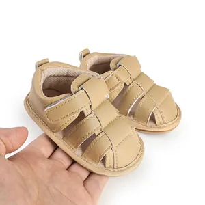 Detailed close-up view of tan breathable faux leather baby sandals held by hand for scale
