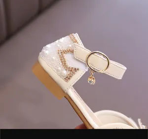 Nahaufnahme eines Mädchenschuhs in Creme mit eleganten Perlen- und Strassdetails.