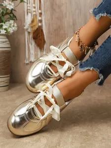 Detailed view of gold metallic GAT sneakers with elegant white ribbon laces