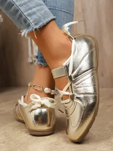 Close-up detail of golden vintage sneakers featuring white ribbon laces and pearl anklet