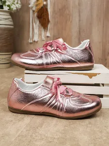 Close-up of rose gold metallic German trainer sneakers with elegant satin ribbon laces