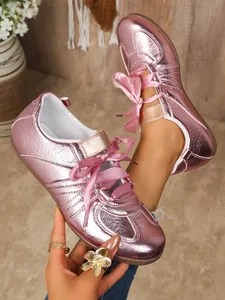 Detailed view of metallic pink GAT sneakers with elegant ribbon laces and shiny finish