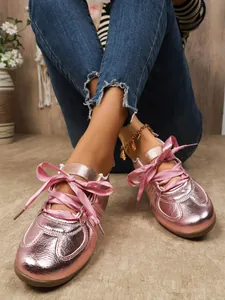 Close-up detail of metallic pink sneakers with elegant satin ribbon shoelace knots