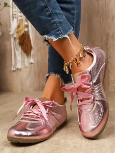 Macro view of pink metallic German training shoes featuring elegant satin ribbon laces