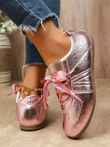 Detailed shot of metallic pink retro flat sneakers featuring elegant silk ribbon bow laces