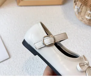 Nahaufnahme von weißen Mädchen Mary Janes mit eleganter Silberschnalle und süßer Schleife