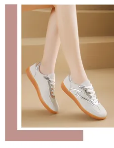 Detalle de zapatillas blancas para mujer estilo German Trainer con toques plateados.