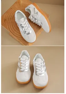 Vista superior de zapatillas blancas con detalles plateados y suelas de goma en fondo neutro.