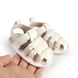 Detailed view of white braided baby sandals with soft breathable soles held by hand