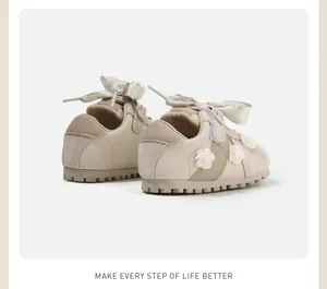 Rear detail view of beige baby girl walking shoes with floral decor and ribbon bow