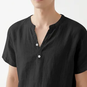 Close-up detail of a men's black linen shirt featuring a stand collar and white buttons.