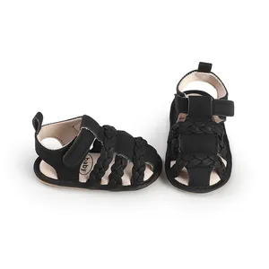 Close-up of black baby walking sandals featuring braided straps and adjustable velcro closure