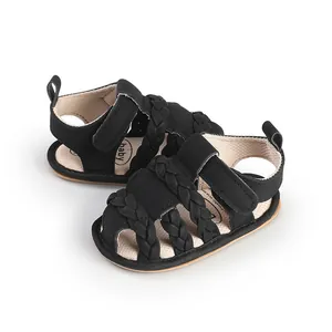 Macro view of black braided baby sandals featuring a soft sole and velcro strap for infants
