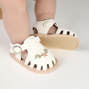 Dettaglio sandali bianchi neonata con ricami floreali e suola morbida antiscivolo