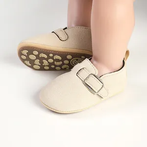 Close-up of beige faux suede baby shoes featuring non-slip footprint sole and metallic buckle