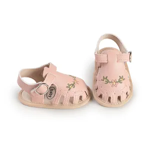 Dettaglio sandali rosa per neonata con delicati ricami floreali su pelle traspirante
