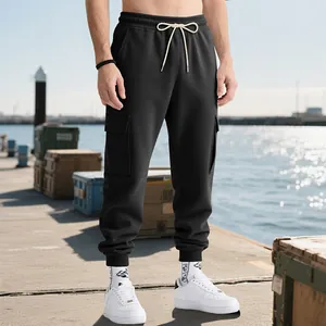 Detailed view of men's black cargo sweatpants worn in an outdoor street style dock setting