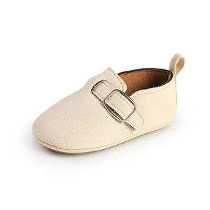 Detailed side view of beige soft nubuck infant shoe with decorative metal buckle strap.