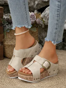 Zijaanzicht van modieuze beige dames sandalen met kurk sleehak en metalen gesp