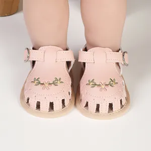Détail montrant des sandales roses pour bébé avec broderie fleurie et semelle souple.