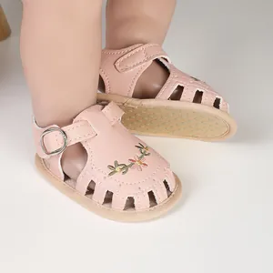 Dettaglio di sandali rosa per neonata con ricami floreali e design traforato traforato