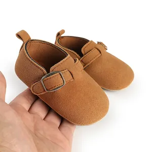 Close-up of brown suede vintage baby loafers with adjustable buckle strap