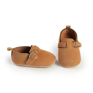 Macro detail of brown frosted suede baby loafers with vintage buckle strap and pull tabs