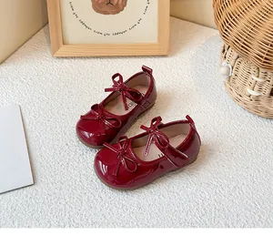 Detailed view of children's burgundy patent leather Mary Jane shoes with lovely bow accents