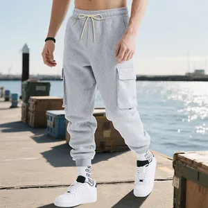 Men's loose cargo sweatpants in grey shown on model in an outdoor dock setting
