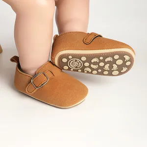 Macro view showing the non-slip sole and side buckle of brown suede baby prewalker shoes